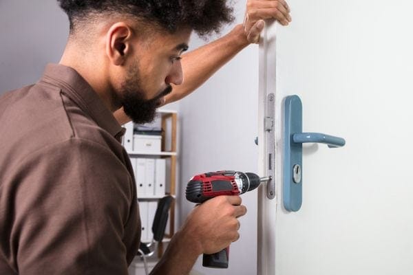 A man using a drill to open a door.